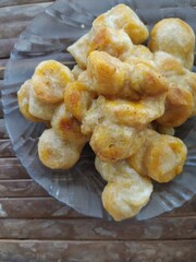 Pisang goreng or fried banana in a plate on wooden table. This is an Indonesian dish made from Banana fried with wheat flour.