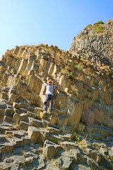 Obraz na płótnie Canvas Traveler Climbing the Symphony of Stones, Massive Basalt Rock Formations Along the Garni Gorge in Armenia