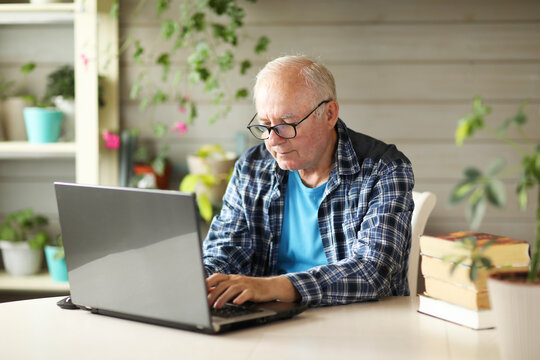 elderly man working on computer while sitting at home