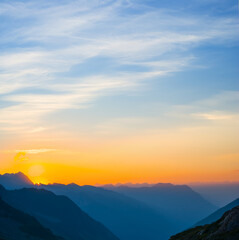 mountain valley silhouette in blue mist at the dramatic sunset