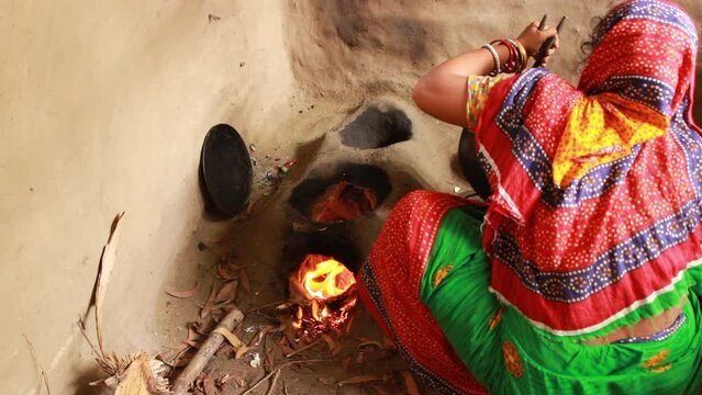 Traditional dressed Indian village woman cooking,  Using traditional clay or mud stove .