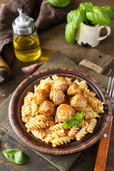 Italian  homemade kitchen. Italian fusilli pasta gluten freewith meat balls in tomato sauce and basil on rustic table.