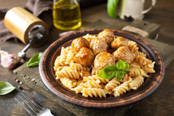Italian  homemade kitchen. Italian fusilli pasta gluten freewith meat balls in tomato sauce and basil on rustic table.