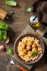 Italian  homemade kitchen. Italian fusilli pasta gluten freewith meat balls in tomato sauce and basil on rustic table. View from above. Copy space.