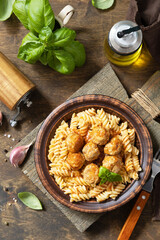 Italian  homemade kitchen. Italian fusilli pasta gluten freewith meat balls in tomato sauce and basil on rustic table. View from above.