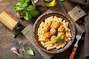 Italian  homemade kitchen. Italian fusilli pasta gluten freewith meat balls in tomato sauce and basil on rustic table. View from above.