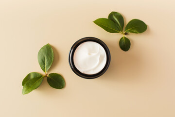 An open jar with cosmetics, a white moisturizer with a natural composition on a beige background...