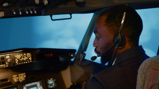 African american copilot using airplane command to fly plane, throttling power engine to takeoff. Control panel navigation with radar compass and dashboard in captain cabin. Handheld shot. Close up.
