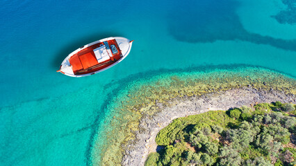 Aerial drone top down photo of beautiful red fishing boat anchored in small paradise island of Monolia in small complex of Lihadonisia with emerald clear sea, North Evia island, Greece