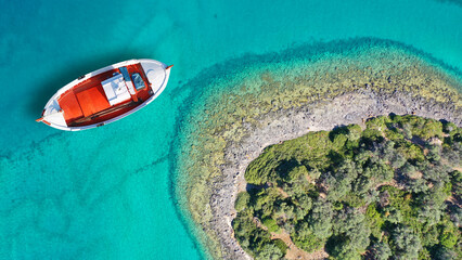 Aerial drone top down photo of beautiful red fishing boat anchored in small paradise island of...
