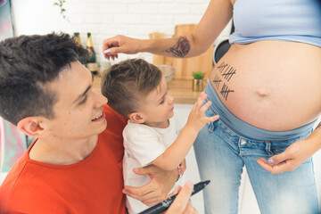 little kid counting weeks of his pregnant mother with parents, happy family concept. High quality photo