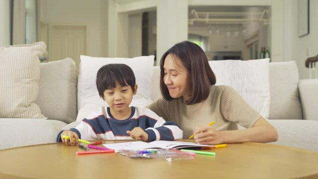 Portrait of happy smiling Asian Family. A student drawing a picture at home or house in family relationship. Love of mother, and son. People lifestyle. Education activity.