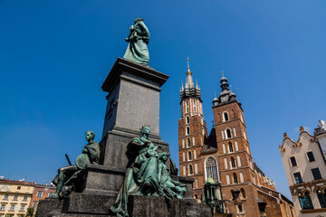 Fototapeta na wymiar monument to Adam Mickiewicz, 1898, in front of Gothic towers of St. Mary's Basilica (Kościół Mariacki), Rynek Główny, Kraków, Poland