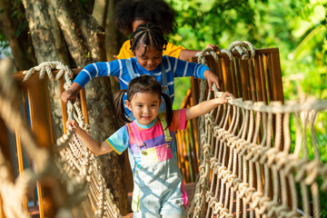 Group of Happy Little boy and girl friends playing and climbing rope net together at playground park on summer vacation. Children kid enjoy outdoor activity playing and learning at school playground