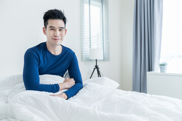 Portrait of Asian young handsome male gay sitting on bed and smile. 