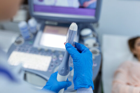 Gynecologist places ultrasound probe cover on a transvaginal ultrasound scanner for vaginal examination of a woman