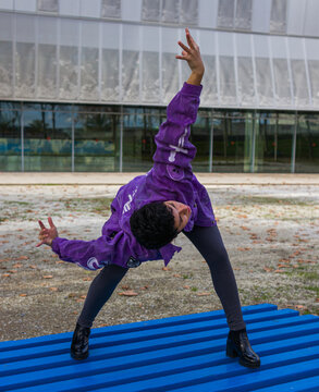 full length image of a woman doing butoh dance moves on a platform of blue boards in a public place