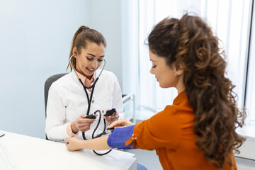 Doctor using sphygmomanometer with stethoscope checking blood pressure to a patient in the hospital.