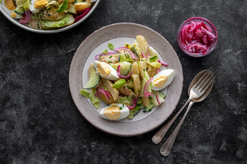 Potato salad with eggs, cucumbers and red pickled onions. Delicious healthy summer salad. Dark background.