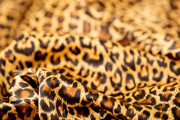 Satin fabric close up background and texture with place for text. Leopard print, silk orange.
