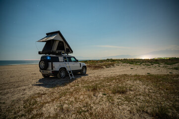 Camping on the beach with 4x4 all terrain vehicle and roof tent - adventurous expedition