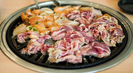 Raw beef slice for barbecue japanese style, yakiniku. Meats are being cooked on stove in a japanese restaurant.