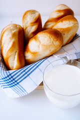 Fresh milk buns on kitchen towel, glass of milk. natural bio product