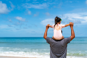 Happy Asian family grandfather carrying and playing with little grandchild girl while walking on the beach on summer vacation. Senior man and child girl kid enjoy outdoor lifestyle together at the sea