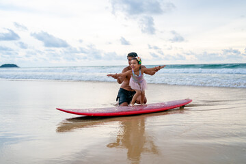Happy Asian family grandfather teaching little grandchild girl surfing on surfboard at the beach....