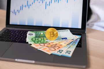 Euro currency and bitcoin on a background laptop with charts. Bitcoins growth chart.