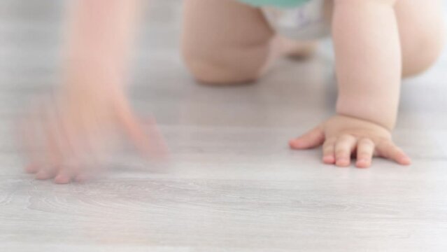 baby bows crawls on wooden grey color floor.toddler is moving fast to camera direction.first steps.