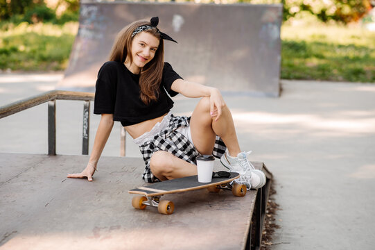 Stylish teenager girl with skateboard sitting and chilling in the skaters park