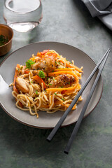 Stir fry noodles with chicken meat and vegetable, dark background. Asian style food, homemade food