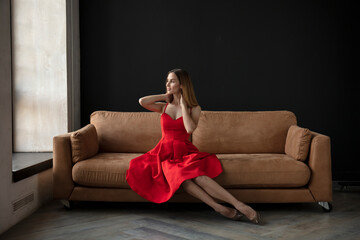 Obraz premium young beautiful woman sitting on a sofa near the window