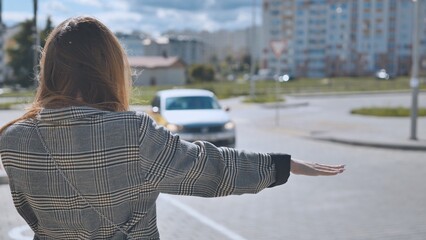 Fototapeta na wymiar A girl is waving to a cab in the city.