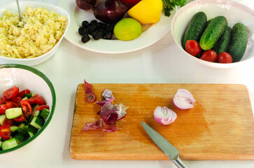 Red onion with peels on a wooden cutting board. The process of preparing Orzo salad with ingredients on the table. The concept of vegetarian food. Horizontal orientation.
