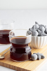 Cups of fresh coffee and a liquorice candies on white table