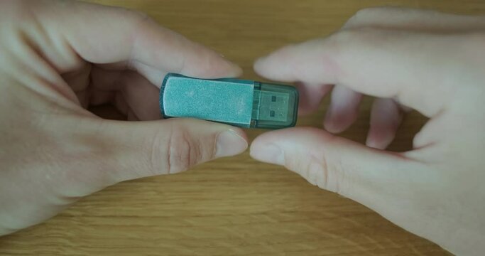 Man's hand holds flash drive, open the connector with protective cap. Close up, desktop
