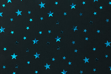 Naklejka na ściany i meble Festive blue silver stars on black decorating paper background. Backdrop for postcards or banners. New year 2023 decoration packaging. Merry xmas or birthday concept