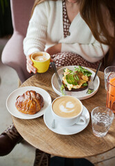 young woman at brunch eating and drinking coffee and avocado toast, millennial lifestyle with food. hipster cafe and restaurant. woman at brunch on weekend