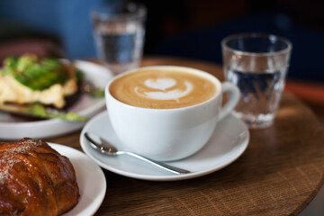 white cup of coffee closeup. Cappuccino at specialty coffee cafe. Coffee house and work of barista. Arabica 100% and glass of water