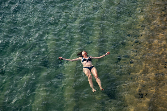top view of woman floating in the sea near sandy beach