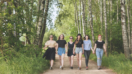 Obraz premium Schoolgirl friends are walking outside the city along a forest road.