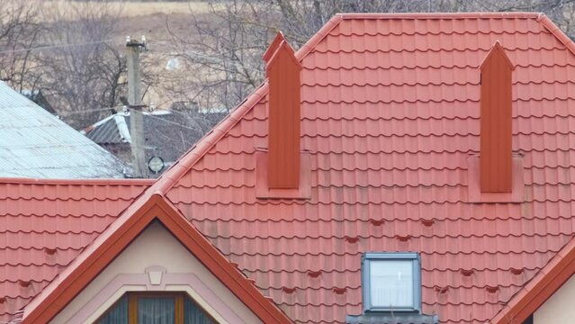 Chimney on house roof top covered with metallic shingles under construction. Tiled covering of building. Real estate development