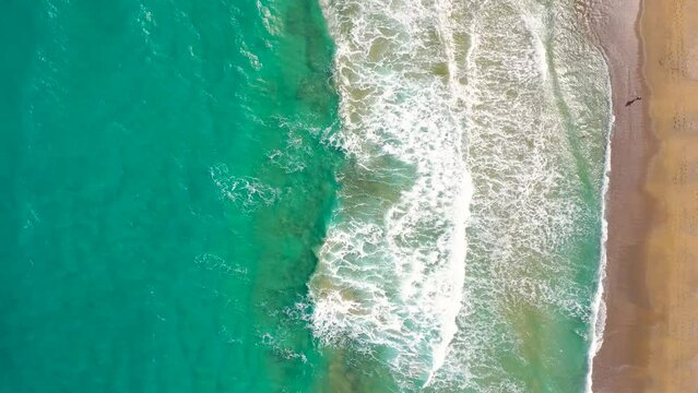 Aerial view of the Mediterranean coast, waves reach the deserted sandy beach. Beautiful vacation and tourism destination in Crete, Greece.