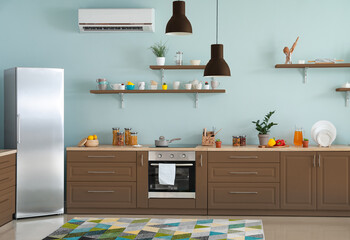 Interior of modern comfortable kitchen with brown furniture and refrigerator