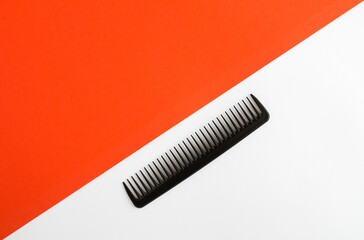 Black comb on the white and red background.Top view. Copy space.
