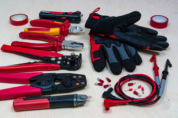 Red professional electrician tools on wood background.