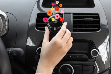 Female driver holding aroma air freshener in car salon