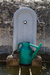 Fototapeta na wymiar arrosoir vert se remplissant d'eau à une fontaine publique